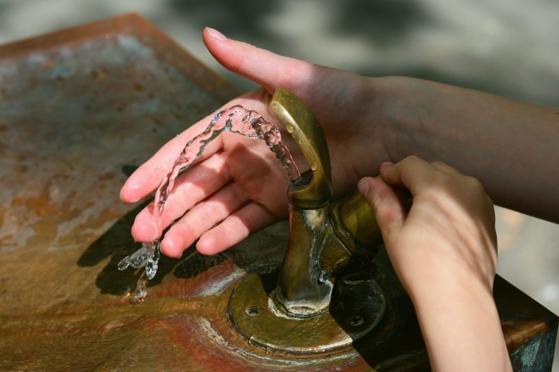 Hände an einem Trinkwasserbrunnen